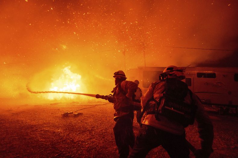 Bomberos rocían agua sobre el incendio Hughes en Castaic, California, el miércoles 22 de enero de 2025. (AP Foto/Ethan Swope)