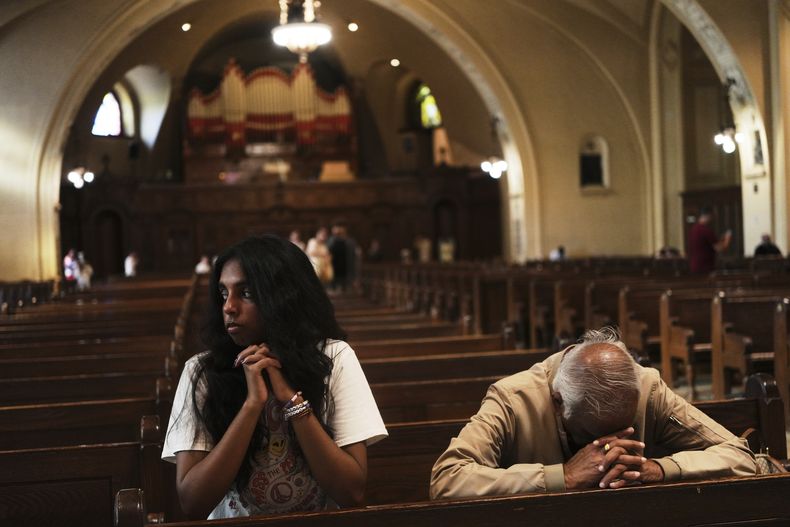 Thurvi Valli y su abuelo, Sitham Valli, rezan dentro de la Iglesia de la Cripta en el santuario de Saint Joseph Mount Royal, en Montreal, el sábado 28 de junio de 2025. (AP Foto/Luis Andrés Henao)