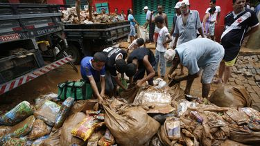 americateve | Varias personas recolectan alimentos empapados de lodo y lluvia afuera de un supermercado en la municipalidad de Itaguacu, estado Espirito Santo, Brasil, el mi&eacute;rcoles 25 de diciembre de 2013. (Foto AP/Vitor Jubino-A Gazeta)
