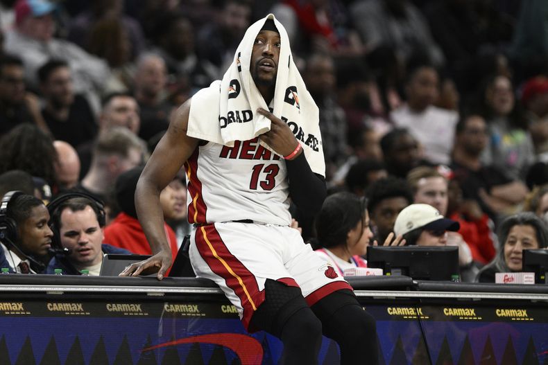 El pívot del Heat de Miami Bam Adebayo (13) se sienta sobre la mesa de anontadores mientras espera para ingresar durante la segunda mitad del juego de baloncesto de la NBA ante los Wizards de Washington, el domingo 31 de marzo de 2024, en Washington. (AP Foto/Nick Wass)