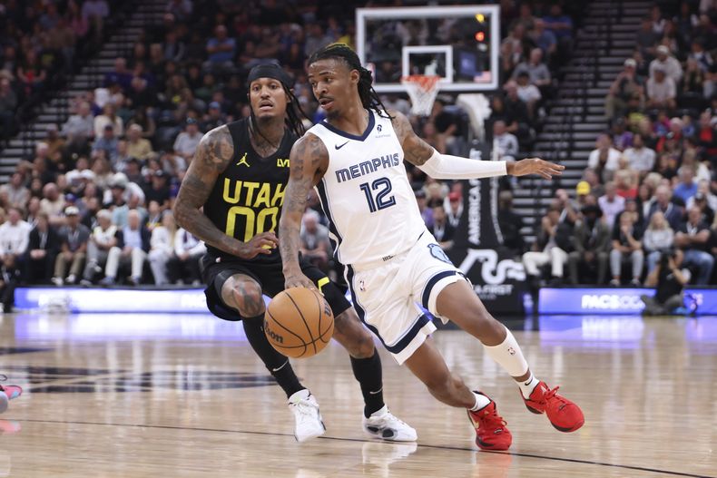 Ja Morant (12), de los Grizzlies de Memphis, maneja el balón ante la mirada de Jordan Clarkson (00), del Jazz de Utah, durante la primera mitad del partido de baloncesto de la NBA, el miércoles 23 de octubre de 2023, en Salt Lake City. (AP Foto/Rob Gray)