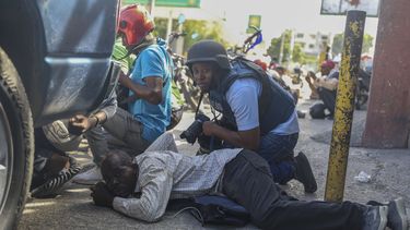 Periodistas se cubren del cruce de disparos entre pandillas y la policía en Puerto Príncipe, Haití, el lunes 11 de noviembre de 2024. (AP Foto/Odelyn Joseph)