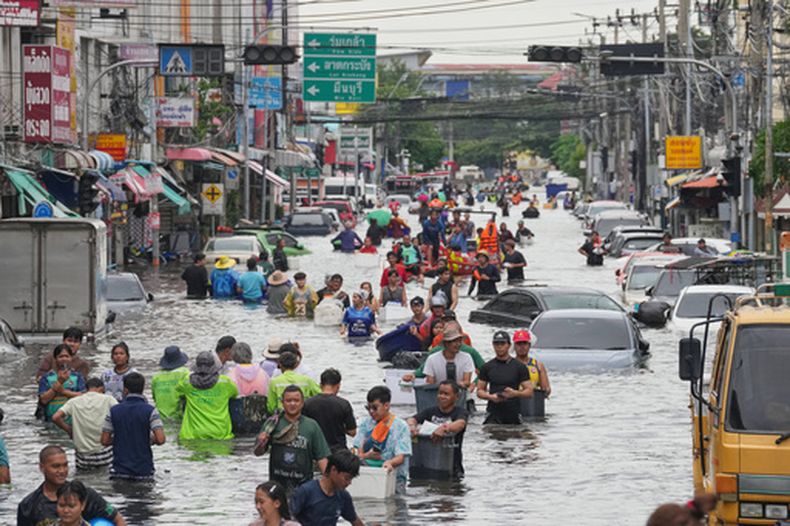 Personas caminan por una calle inundada tras fuertes lluvias en Bangkok, Tailandia, el lunes 28 de septiembre de 2026. (AP Foto/Sakchai Lalit)