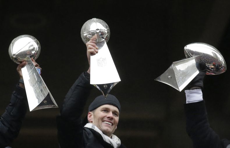 ARCHIVO - El entonces quarterback de los Patriots de Nueva Inglaterra, Tom Brady, sostiene el trofeo Vince Lombardi, entre otros que el equipo había ganado antes, durante un desfile en Boston para celebrar el triunfo de los Patriots en el Super Bowl del 7 de febrero de 2017 sobre los Falcons de Atlanta. (AP Foto/Elise Amendola, archivo)