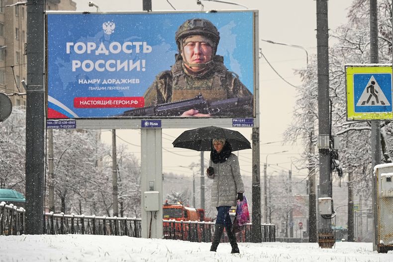 Una persona pasa junto a una valla publicitaria que muestra a un soldado ruso participando en acciones militares en Ucrania y en la que se lee: El orgullo de Rusia, en San Petersburgo, Rusia, el lunes 24 de noviembre de 2025. (Foto AP/Dmitri Lovetsky)