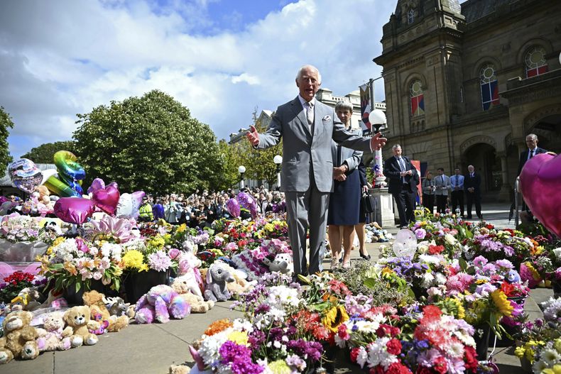 El rey Carlos III de Gran Bretaña mira ofrendas frente al Ayuntamiento de Southport, en Southport, Inglaterra, el martes 20 de agosto de 2024, mientras se reúne con miembros de la comunidad local, luego del ataque del 29 de julio en una clase de baile infantil. (Paul Ellis/Pool vía AP)