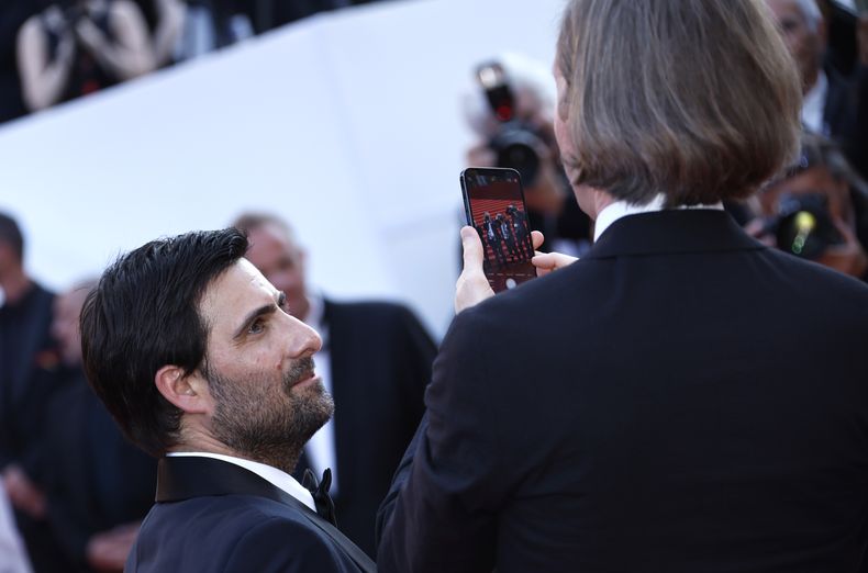 El director Wes Anderson, a la derecha, toma una fotografía a los fotógrafos de la alfombra roja mientras el actor Jason Schwartzman observa, al llegar al estreno de la película Asteroid City en la 76a edición del Festival de Cine de Cannes, en el sur de Francia, el martes 23 de mayo de 2023. (Foto Joel C Ryan/Invision/AP)