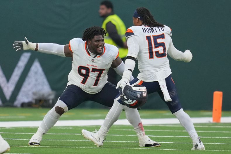El tackle defensivo de los Broncos de Denver Malcolm Roach y el linebacker Nik Bonitto celebran la victoria ante los Jets de Nueva York el domingo 12 de octubre del 2025. (AP Foto/Kin Cheung)