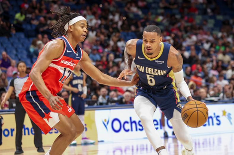 Dejounte Murray (5), base de los Pelicans de Nueva Orleans, intenta conducir el balón ante Tre Johnson (12), base de los Wizards de Washington, en la primera mitad de un juego de baloncesto de la NBA en Nueva Orleans, el domingo 8 de marzo de 2026. (Foto AP/Peter Forest)