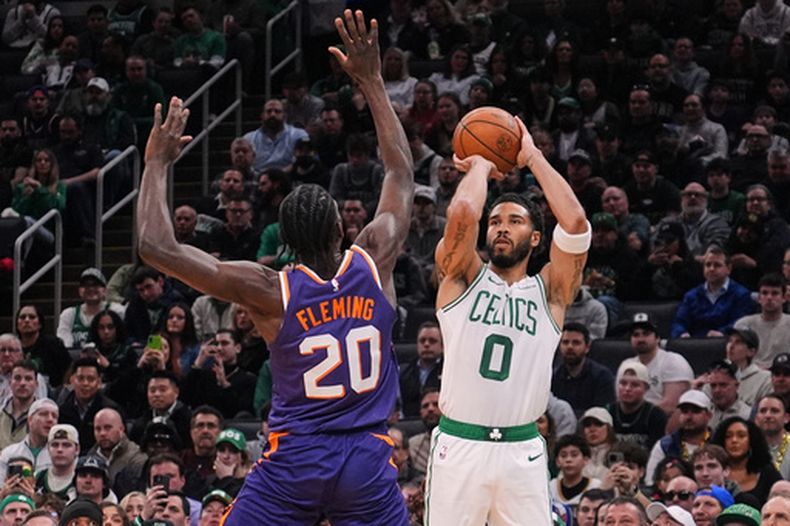 Jayson Tatum (0), de los Celtics de Boston, lanza un triple sobre Rasheer Fleming (20), de los Suns de Phoenix, durante la primera mitad del juego de baloncesto de la NBA, el lunes 16 de marzo de 2026, en Boston. (AP Foto/Charles Krupa)