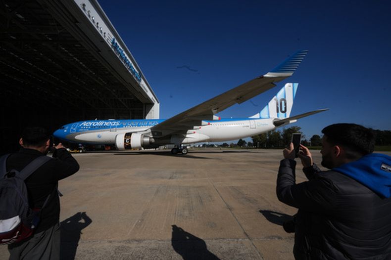 Periodistas toman fotografías del avión de Aerolíneas Argentinas que transportará a la selección nacional de fútbol de Argentina durante la Copa Mundial de la FIFA 2026, en el Aeropuerto Internacional Ministro Pistarini en Ezeiza, Argentina, el viernes 22 de mayo de 2026. (AP Foto/Gustavo Garello)