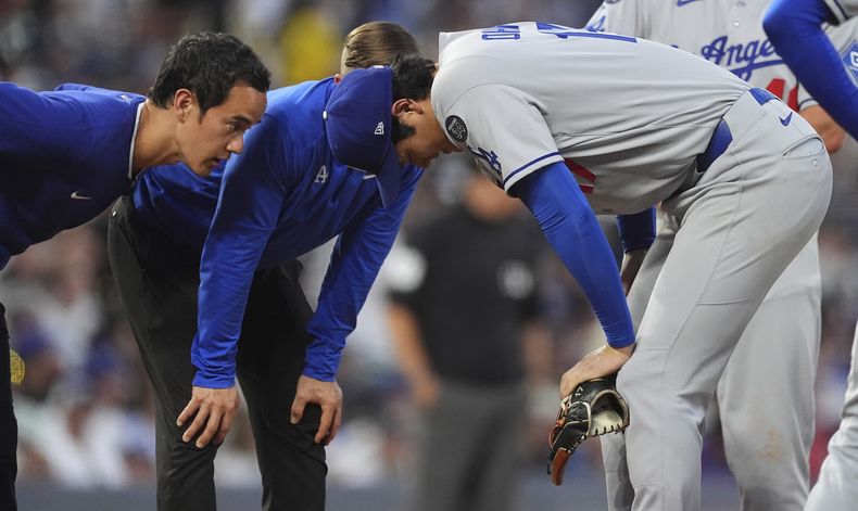 El japonés Shohei Ohtani, abridor de los Dodgers de Los Ángeles, recibe atención tras llevarse un pelotazo en el juego ante los Rockies de Coloorado, el miércoles 20 de agosto de 2025 (AP Foto/David Zalubowski)