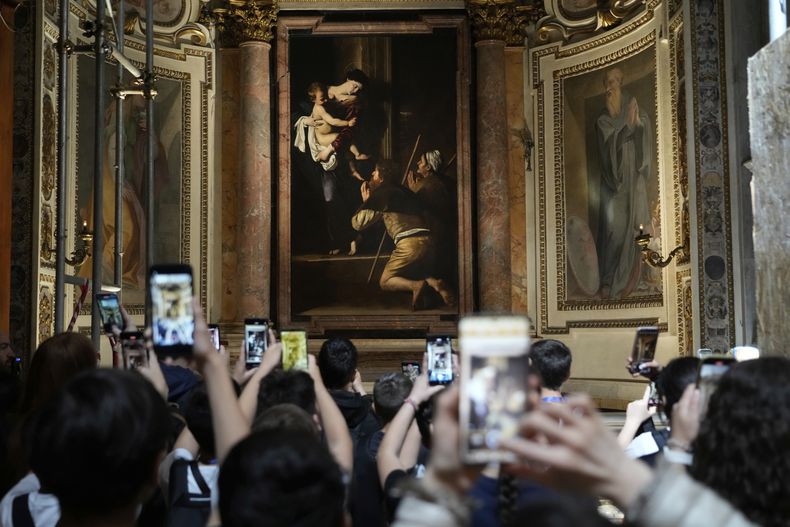 Turistas admiran La Madonna de los Peregrinos, de Caravaggio, en la Basílica de San Agustín, en Roma, el jueves 22 de mayo de 2025. (AP Foto/Gregorio Borgia)