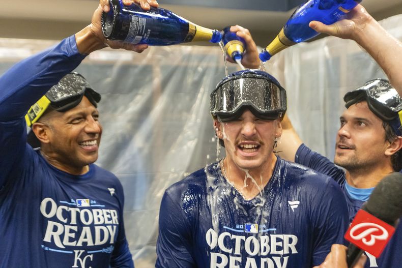 Bobby Witt Jr. (centro), de los Reales de Kansas City, es empapado en champaña tras la clasificación a los playoffs pese a una derrota ante los Bravos de Atlanta, el viernes 27 de septiembre de 2024 (AP Foto/Jason Allen)