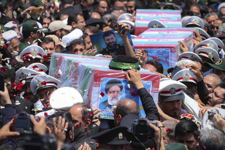 En esta imagen distribuida por la oficina de la presidencia de Irán, los ataúdes cubiertos con la bandera nacional del presidente, Ebrahim Raisi, y de sus acompañantes fallecidos en un accidente de helicóptero, durante su cortejo fúnebre en la ciudad de Mashhad, Irán, el 23 de mayo de 2024. (Presidencia de Irán vía AP)