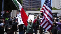 Un manifestante sostiene una bandera de México y una de Estados Unidos durante una protesta contra las redadas migratorias, el martes 10 de junio de 2025, en Los Ángeles. (AP Foto/Damian Dovarganes)