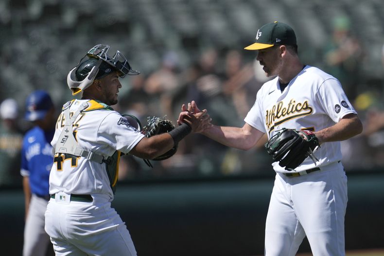El venezolano Carlos Pérez, cátcher de los Atléticos de Oakland, festeja con el lanzador Trevor May, tras el duelo del miércoles 6 de septiembre de 2023, ante los Azulejos de Toronto (AP foto/Jeff Chiu)