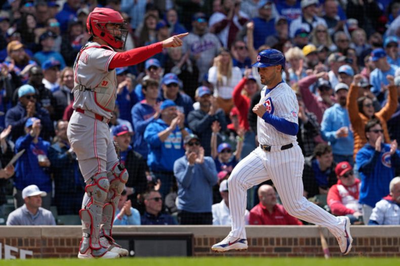 Michael Conforto (derecha) anota una carrera para los Cachorros de Chicago frente al receptor Tyler Stephenson de los Rojos de Cincinnati, el jueves 7 de mayo de 2026, en Chicago. (AP Foto/Nam Y. Huh)