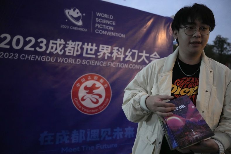 Tao Bolin, un influencer de 25 años y fanático de la ciencia ficción, sostiene una copia firmada de El problema de los tres cuerpos fuera de la Convención Mundial de Ciencia Ficción en Chengdu, provincia de Sichuan, el viernes 20 de octubre de 2023. El problema de los tres cuerpos, escrita por el ingeniero Liu Cixin, ayudó a la ciencia ficción china a abrirse paso a nivel internacional, ganando premios y llegando a las listas de lectura de personas como el ex presidente estadounidense Barack Obama y Mark Zuckerberg. (AP Photo/Ng Han Guan)