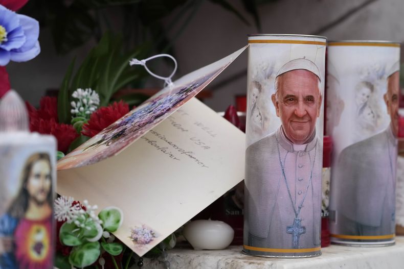 Velas con la imagen del papa Francisco se ven a los pies de la estatua al fallecido papa Juan Pablo II ante la Policlínica Agostino Gemelli en Roma, el miércoles 19 de febrero de 2025, donde el papa está hospitalizado desde el viernes 14 de febrero. (AP foto/Gregorio Borgia)