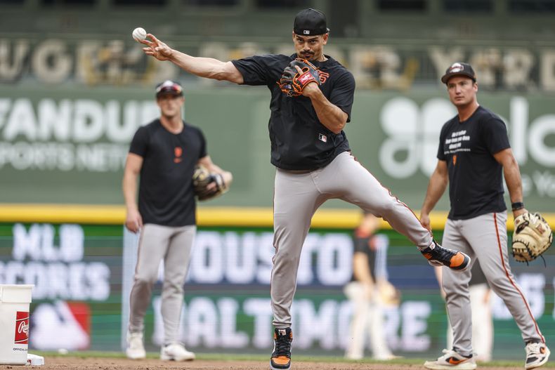 Willy Adames, centro, campocorto de los Gigantes de San Francisco, calienta previo al partido de béisbol de Grandes Ligas frente a los Cerveceros de Milwaukee, el viernes 22 de agosto de 2025, en Milwaukee. (AP Foto/Jeffrey Phelps)