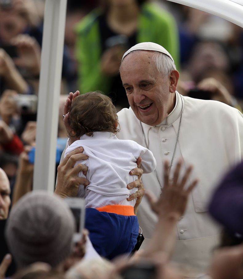 El papa Francisco acaricia a un ni&ntilde;o en camino a su audiencia general de los mi&eacute;rcoles en la plaza de San Pedro en El Vaticano el 9 de abril de 2014. (Foto de AP/Gregorio Borgia)