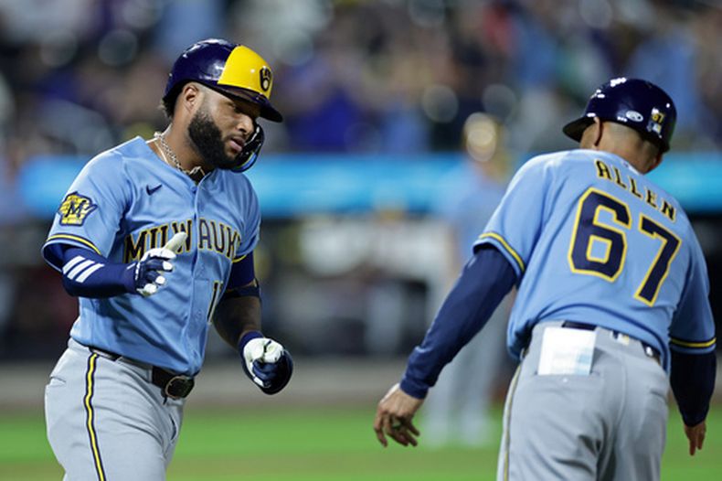 El venezolano Jackson Chourio (izquierda) festeja con el coach de la inicial Spencer Allen, luego de batear un jonrón en el encuentro del jueves 27 de agosto de 2026 ante los Mets de Nueva York (AP Foto/Adam Hunger)