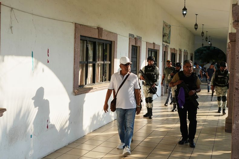 Guadalupe Mora camina con escolta policial y de la Guardia Nacional por La Ruana, en el estado mexicano de Michoacán, el 20 de noviembre de 2025. (AP Foto/Eduardo Verdugo)
