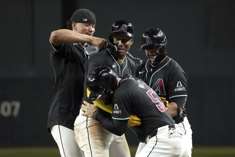 El dominicano Geraldo Perdomo (2do de izquierda a derecha) celebra con sus compañeros de los Diamondbacks de Arizona, tras empujar la carrera del triunfo sobre los Azulejos de Toronto, el viernes 12 de julio de 2024 (AP Foto/Rick Scuteri)