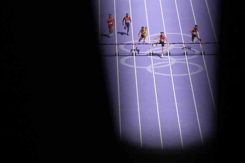Los corredores compiten en un repechaje de los 400 metros con vallas de hombres en el atletismo de los Juegos Olímpicos de París, el martes 6 de agosto de 2024, en Saint-Denis, Francia. (AP Foto/Ashley Landis)