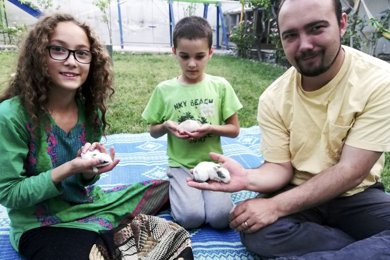 Esta foto familiar muestra a Ryan Corbett sosteniendo conejos con su hija Miriam y su hijo Caleb en Kabul, Afganistán, en 2020. (Anna Corbett via AP)