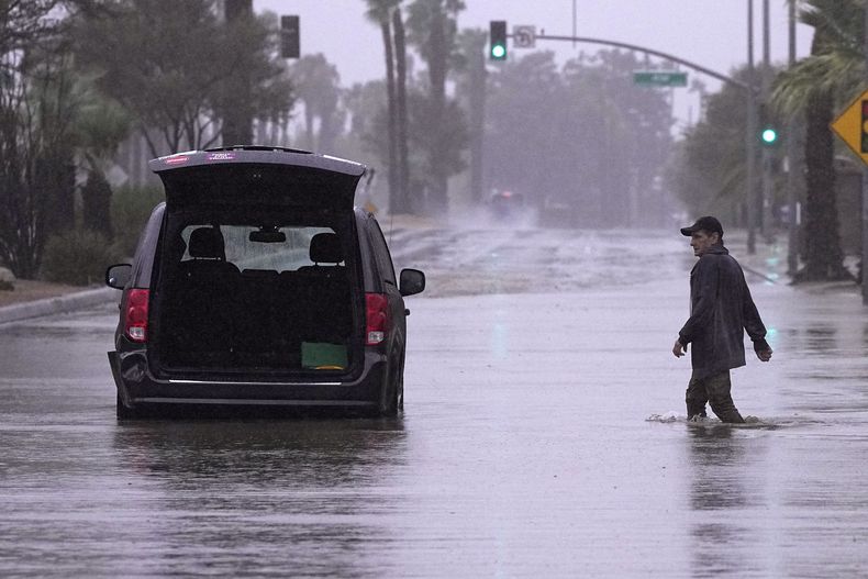 Un conductor acude a retirar pertenencias de su vehículo tras quedar varado en una calle inundada, el domingo 20 de agosto de 2023 en Palm Desert, California. Los meteorólogos advirtieron que la tormenta tropical Hilary era la primera tormenta tropical en golpear el sur de California en 84 años, y planteaba el riesgo a inundaciones, aludes de lodo, tornados aislados, vendavales y cortes de luz. (AP Foto/Mark J. Terrill)