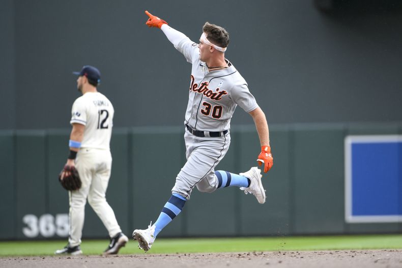 Kerry Carpenter de los Tigres de Detroit apunta hacia donde pegó su jonrón mientras recorre las bases superando al segunda base de los Mellizos de Minnesota Kyle Farmer en el encuentro del domingo 18 de junio del 2023. (AP Foto/Craig Lassig)