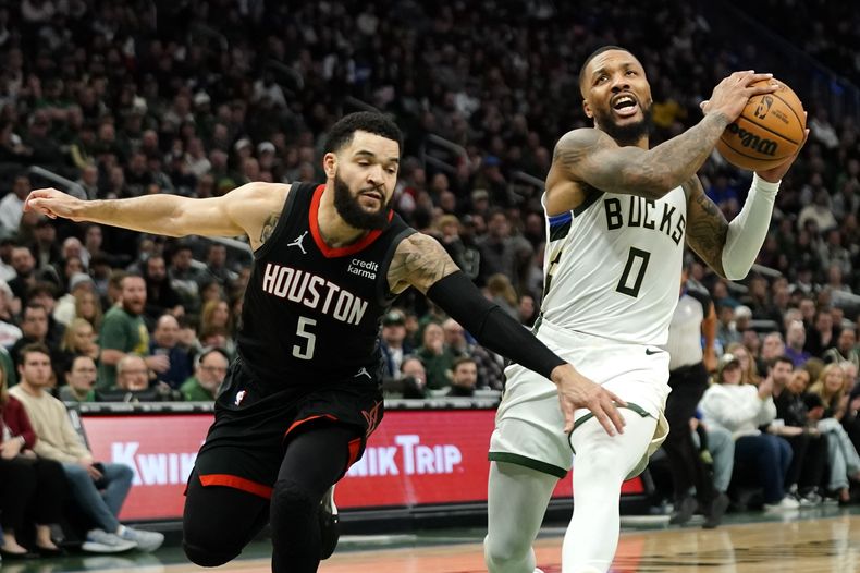 Damian Lillard (0), de los Bucks de Milwaukee, avanza con el balón rumbo a un enceste en contra de los Rockets de Houston, ante la marca defensiva de Fred VanVleet (5) durante la segunda mitad del juego de baloncesto de la NBA, el domingo 17 de diciembre de 2023, en Milwaukee. (AP Foto/Aaron Gash)