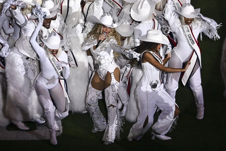 ARCHIVO - Beyoncé, en el centro, se une a su hija Blue Ivy, a la derecha, durante una actuación de medio tiempo en un partido de fútbol americano de la NFL entre los Baltimore Ravens y los Houston Texans, el 25 de diciembre de 2024, en Houston. (Foto AP/Maria Lysaker, archivo)