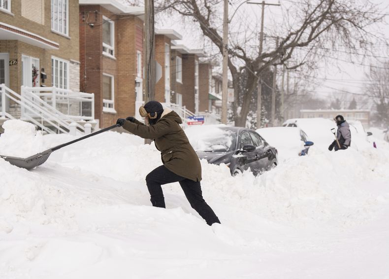 Varias personas quitan la nieve para sacar sus coches en Montreal, el lunes 17 de febrero de 2025, después de que cayeran más de 70 centímetros de nieve en 4 días, batiendo un récord de nevadas en la ciudad. (Christinne Muschi/The Canadian Press via AP)