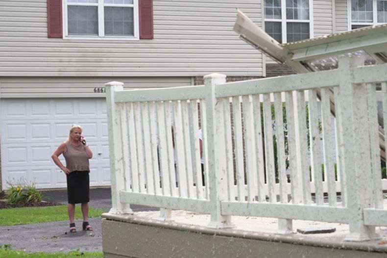 Kerry Hourigan habla por teléfono tras revisar daños causados por una tormenta en su casa de Tinley Park, Illinois, el martes 11 de agosto de 2026. (AP Foto/Laura Bargfeld)