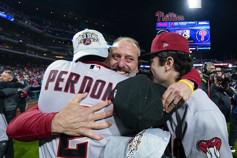Torey Lovullo, manager de los Diamondbacks de Arizona, abraza a los peloteros Geraldo Perdomo y Corbin Carroll, tras ganar el séptimo juego de la Serie de Campeonato de la Liga Nacional ante los Filis de Filadelfia, el martes 24 de octubre de 2023 (AP Foto/Matt Slocum)