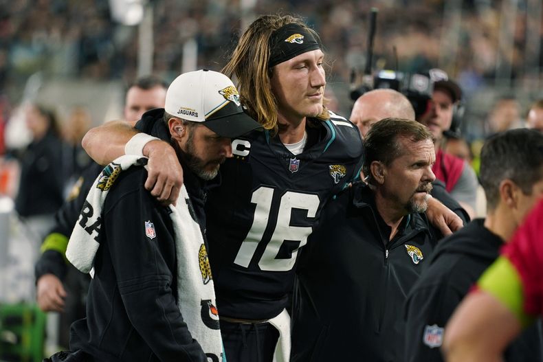 Trevor Lawrence (16), quarterback de los Jaguars de Jacksonville, es asistido para salir del campo de juego después de sufrir una lesión durante la segunda mitad del juego de la NFL en contra de los Bengals de Cincinnati, el lunes 4 de diciembre de 2023, en Jacksonville, Florida. (AP Foto/John Raoux)
