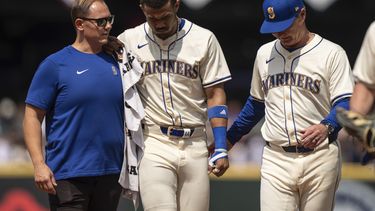 Julio Rodriguez, centro, jardinero central de los Marineros de Seattle, es asistido por el mánager de los Marineros, Scott Servais, derecho, y un entrenador del equipo durante la sexta entrada del juego de béisbol en contra de los Astros de Houston, el domingo 21 de julio de 2024, en Seattle. (AP Foto/Stephen Brashear)