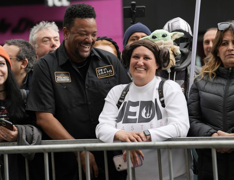 Otis Farrell, izquierda, y Bertha Channell, de Anaheim, California vestidos con disfraces de Star Wars esperan en una acera antes de una ceremonia en honor a la fallecida actriz Carrie Fisher quien recibió una estrella póstuma en el Paseo de la Fama de Hollywood el 4 de mayo de 2023. La fecha se conoce también como Día de Star Wars, en homenaje a las películas de Star Wars en las que Fisher interpretó a la Princesa Leia. (Foto AP/Chris Pizzello)