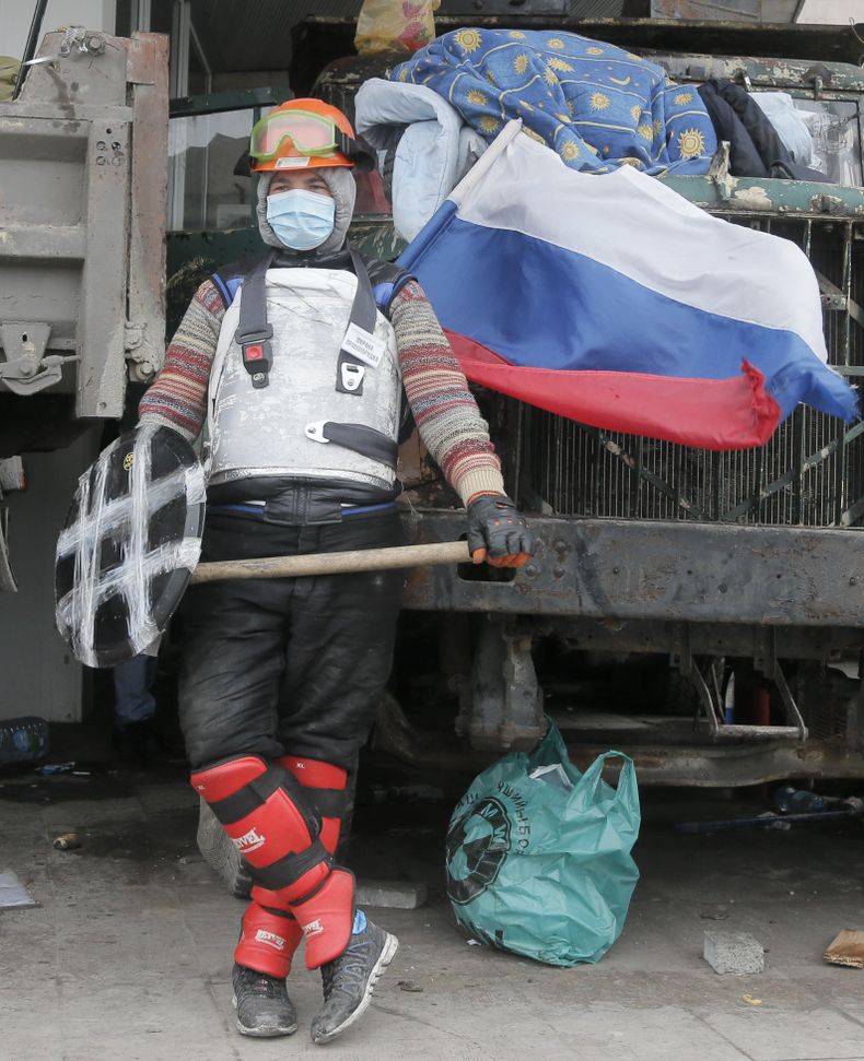 Un activista pro ruso vigila un edificio administrativo regional tomado por su grupo en Donetsk, Ucrania, el viernes 11 de abril de 2014. A la derecha se aprecia la bandera rusa. (Foto AP/Efrem Lukatsky)