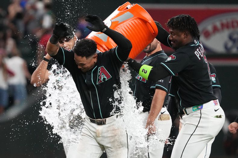 El venezolano Ildemaro Vargas, de los Diamondbacks de Arizona, es empapado por su compañero, el dominicano Geraldo Perdomo, luego de resolver con un sencillo el duelo ante los Atléticos, el martes 21 de julio de 2026 (AP Foto/Rick Scuteri)