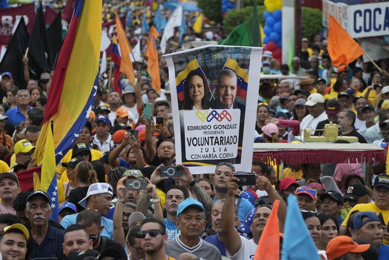 ARCHIVO - Un simpatizante muestra un cartel con las imágenes de los líderes de la oposición María Corina Machado y Edmundo González durante un acto de campaña el jueves 2 de mayo de 2024, en Maracaibo, Venezuela. (AP Foto/Ariana Cubillos, archivo)