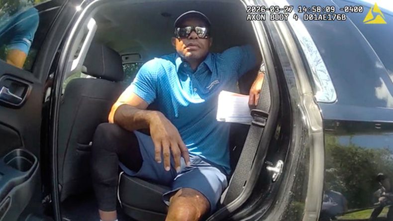 ARCHIVO - En esta imagen de un video grabado con la cámara corporal de un agente de policía y difundido por la Oficina del Sheriff del Condado de Martin, Florida, el golfista Tiger Woods aparece sentado en un vehículo policial sin distintivos mientras habla con agentes del orden público tras un accidente automovilístico en Jupiter Island, Florida, el 27 de marzo de 2026. (Oficina del Sheriff del Condado de Martin vía AP, Archivo)
