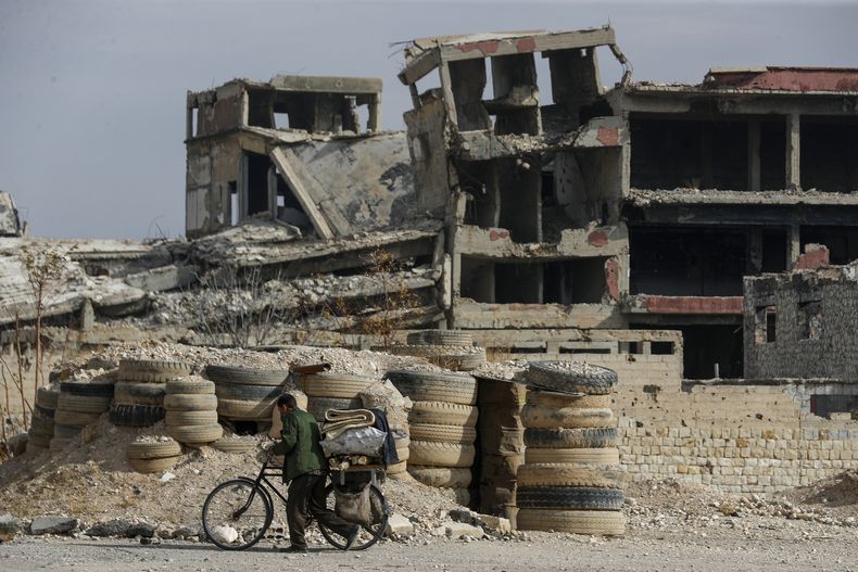 Un hombre empuja su bicicleta por una calle de Harasta, al este de Damasco, Siria, el jueves 12 de diciembre de 2024. (AP Foto/Omar Sanadiki)