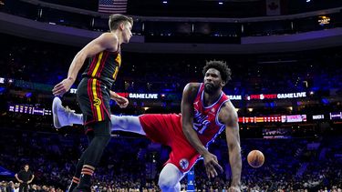 Joel Embiid de los 76ers de Filadelfia (derecha) pierde control del balón mientras cae próximo a Bogdan Bogdanovic de los Hawks de Atlanta durante la primera mitad del juego de la NBA, el viernes 8 de diciembre de 2023, en Filadelfia. (AP Foto/Chris Szagola)