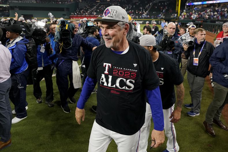 ARCHIVO - El mánager de los Rangers de Texas Bruce Bochy (centro) celebra junto a su equipo de trabajo en el terreno luego del tercer juego de la serie divisional de la Liga American ante los Orioles de Baltimore, el martes 10 de octubre de 2023, en Arlington, Texas. (AP Foto/Tony Gutierrez, file)