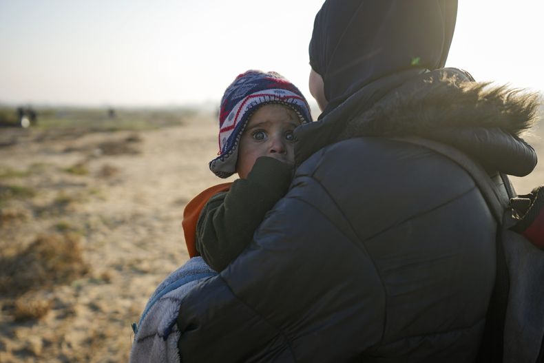 Una mujer palestina carga a su bebé mientras regresan a su hogar en el norte de la Franja de Gaza después de que Israel anunció su decisión de permitir el regreso de miles de ellos por primera vez desde las primeras semanas de la guerra con Hamás, el lunes 27 de enero de 2025. (AP Foto/Abdel Kareem Hana)