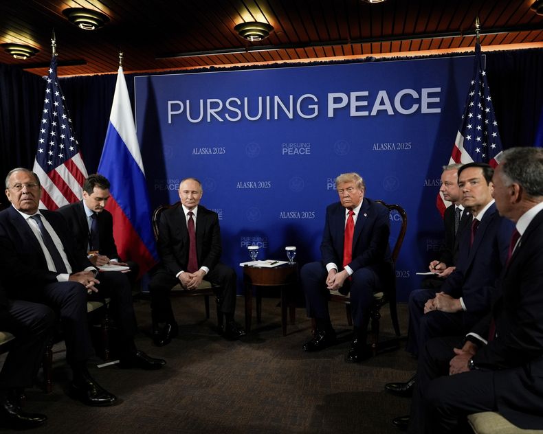 El presidente Donald Trump se reúne con su homólogo ruso Vladímir Putin el viernes 15 de agosto de 2025, en la Base Conjunta Elmendorf-Richardson, Alaska. A la izquierda se encuentra el ministro de Relaciones Exteriores de Rusia, Serguei Lavrov. El segundo de derecha a izquierda es el secretario de Estado estadounidense Marco Rubio. El letrero del fondo dice: En busca de la paz. (AP Foto/Julia Demaree Nikhinson)